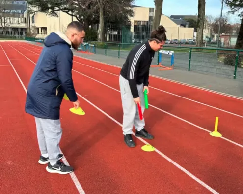 Deux personnes préparent une piste d&#039;athlétisme.